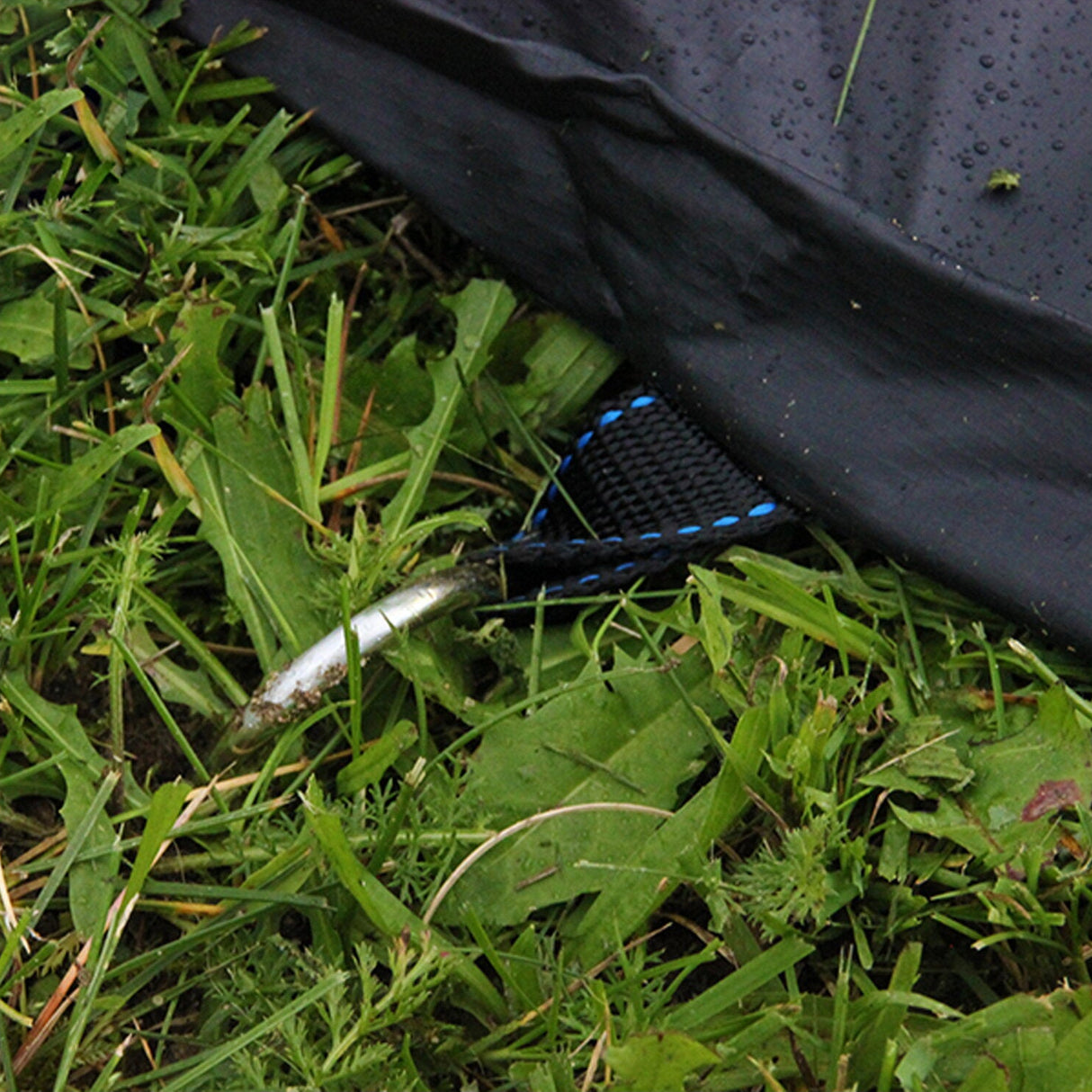 black trampoline cover being anchored into grass