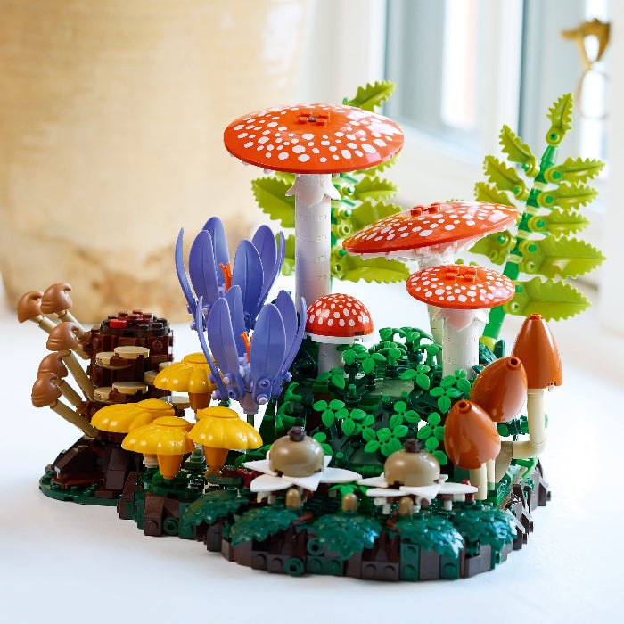 LEGO-like forest scene with mushrooms and plants on a white surface