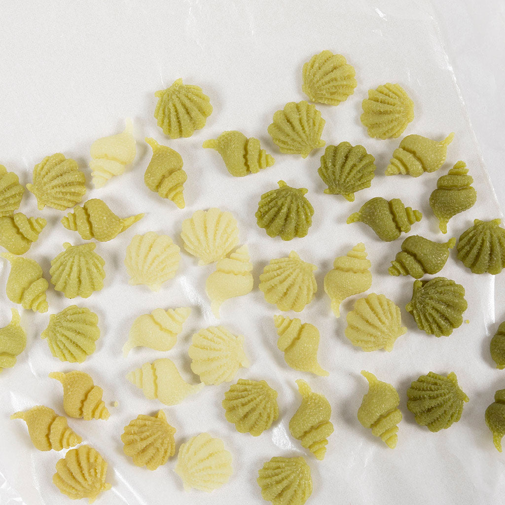 Green shell-shaped pasta on a white surface