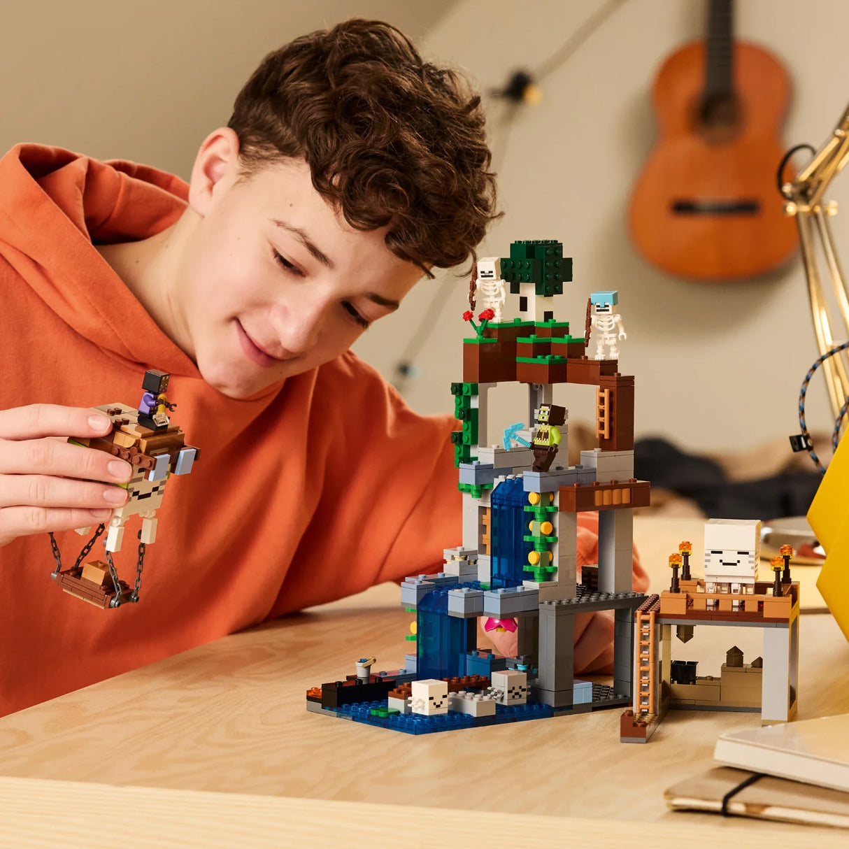 Child playing with a LEGO set on a table, with a guitar in the background.