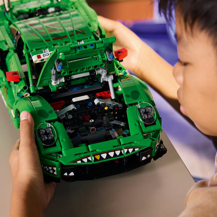 Child playing with a green toy vehicle made of interlocking bricks.