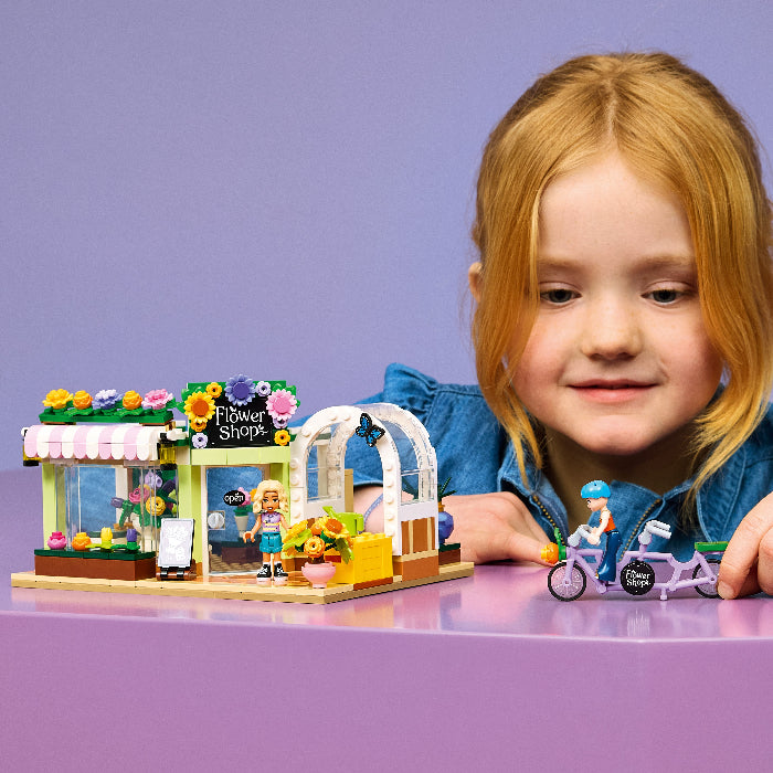 Child with a LEGO Flower Shop set on a purple background