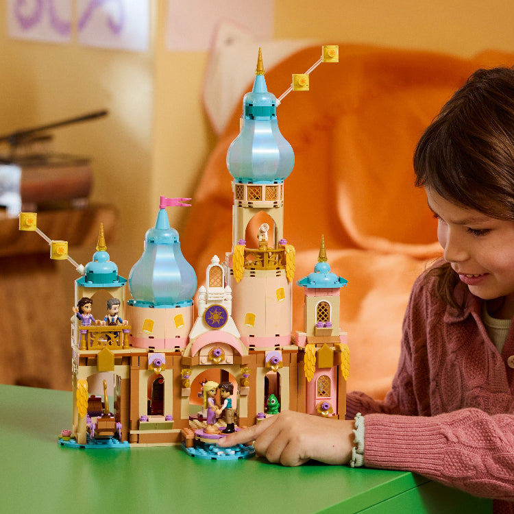 Child playing with a colorful toy castle set on a green table.