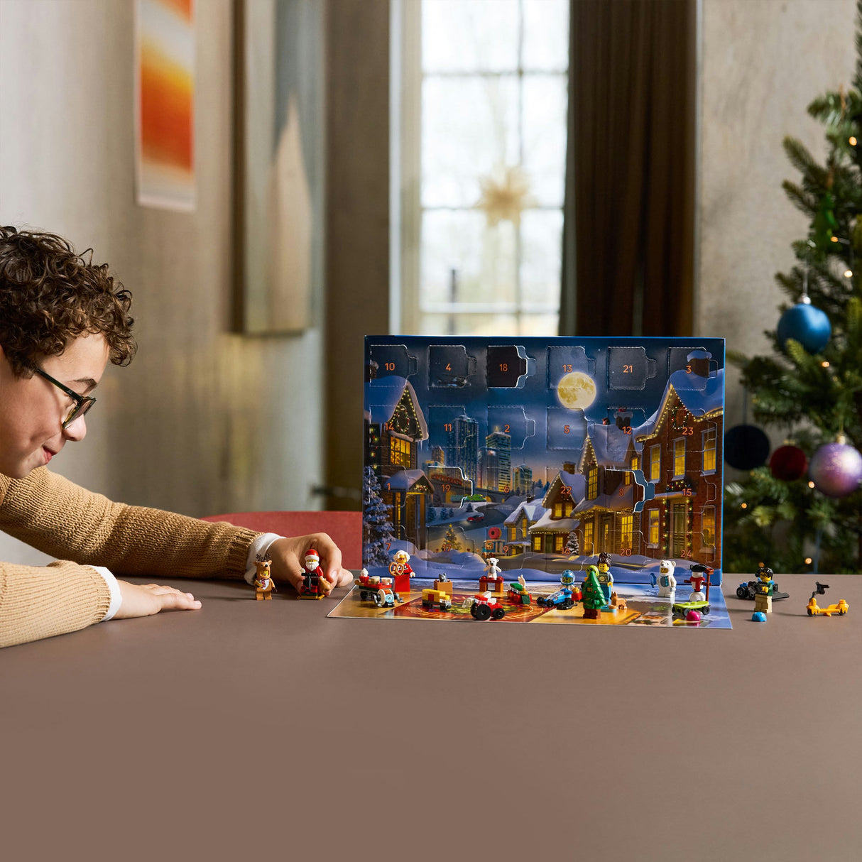 Person interacting with a LEGO Advent calendar in a festive setting with a Christmas tree.