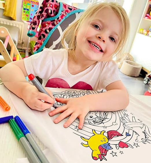 A girl colouring a white tshirt with a unicorn design in a classroom