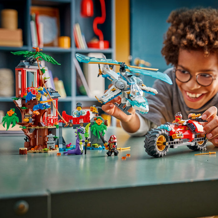 Child playing with toy helicopter and vehicle set on a table with a bookshelf in the background