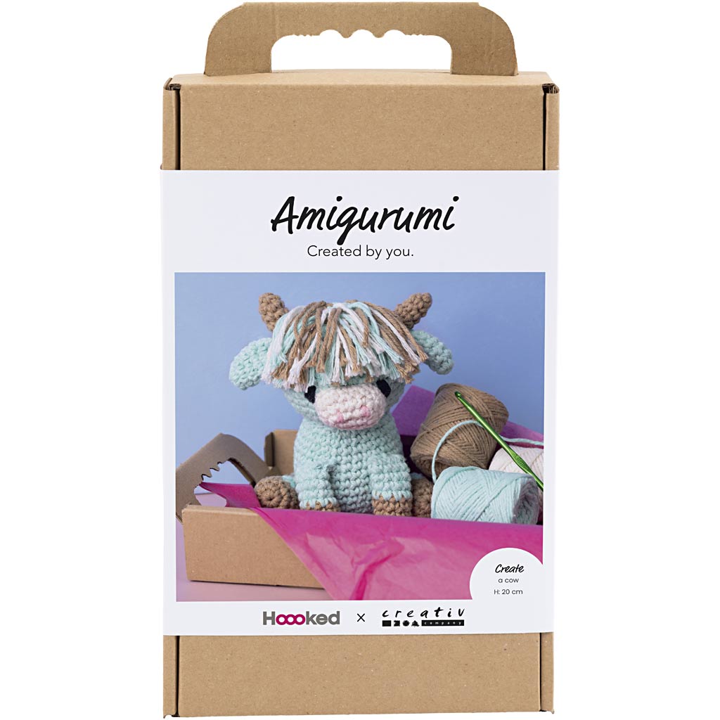 Amigurumi cow packaging with a crochet hook and yarn on a white background