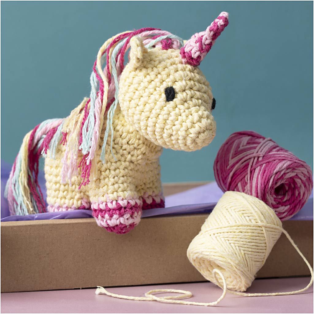 Crocheted unicorn toy with yarn on a purple surface