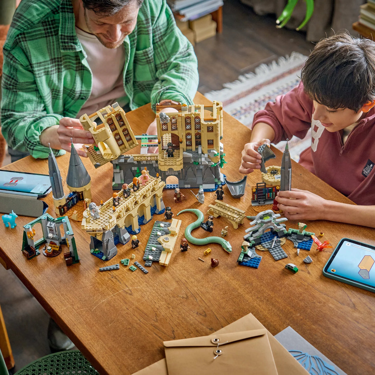 Two people playing with toy building sets on a wooden table.