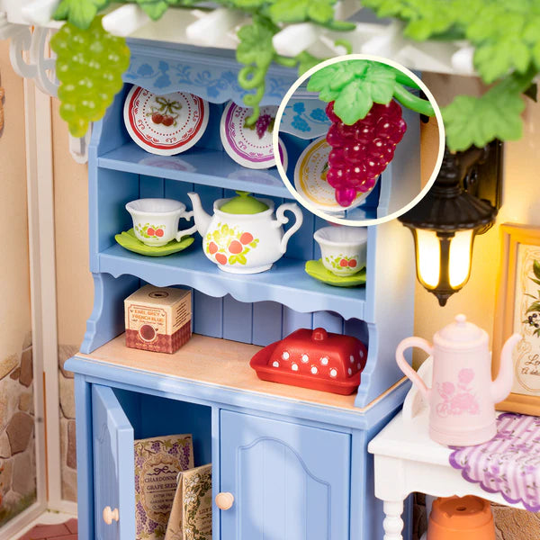 Blue wooden cabinet with miniature tea set and decorative items in a cozy room setting.