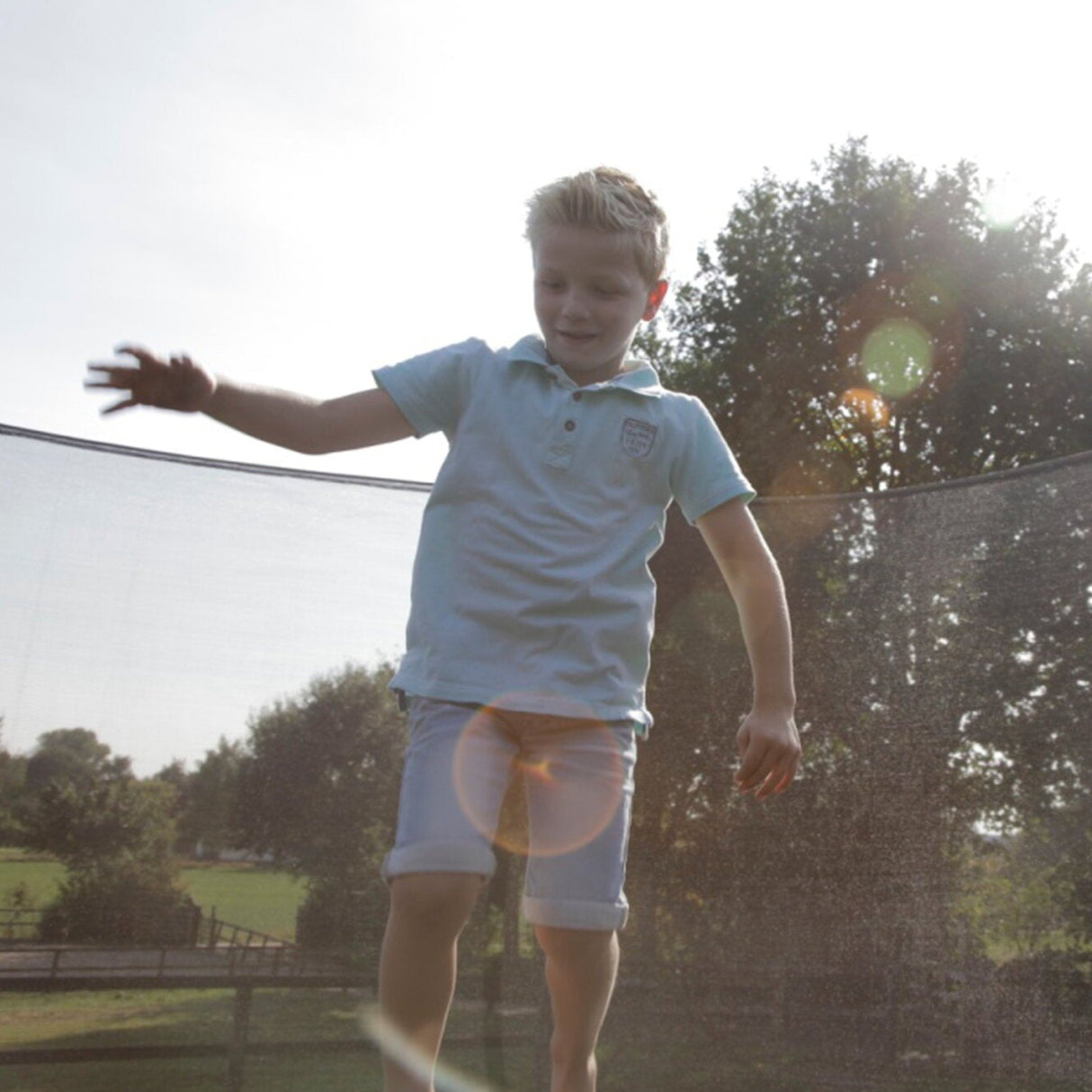child jumping on EXIT Silhouette Ground Trampoline with Safety Net