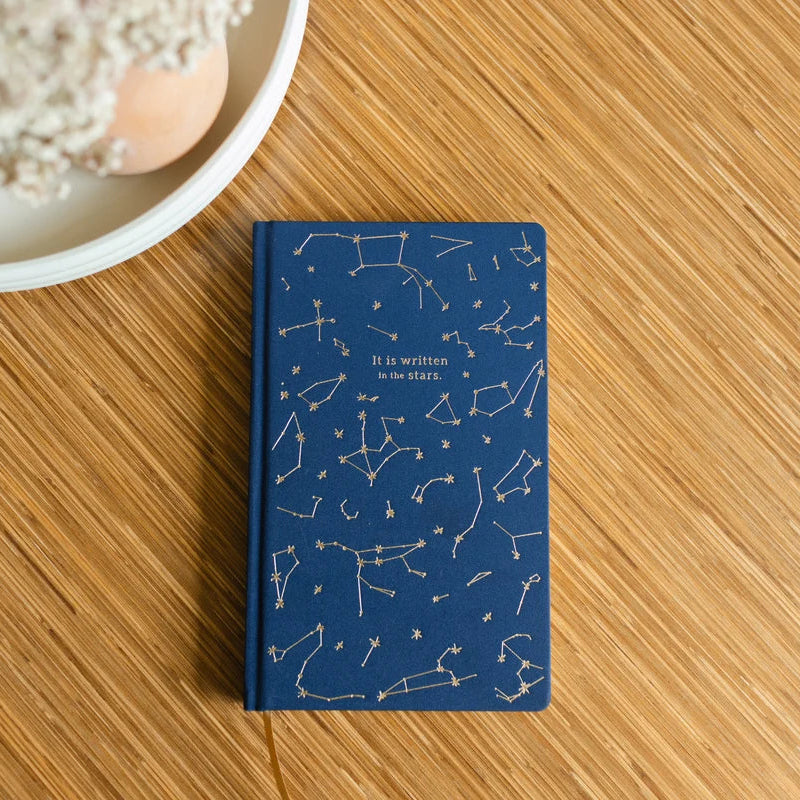 Blue notebook with star constellation design on a wooden surface