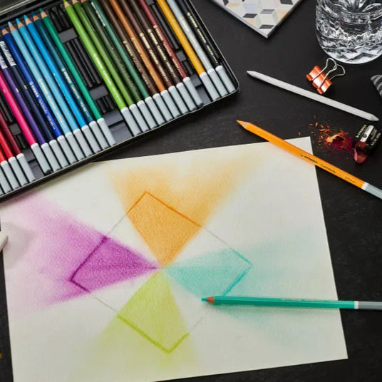 Colorful art supplies including pencils, eraser, and watercolor paper on a dark surface.