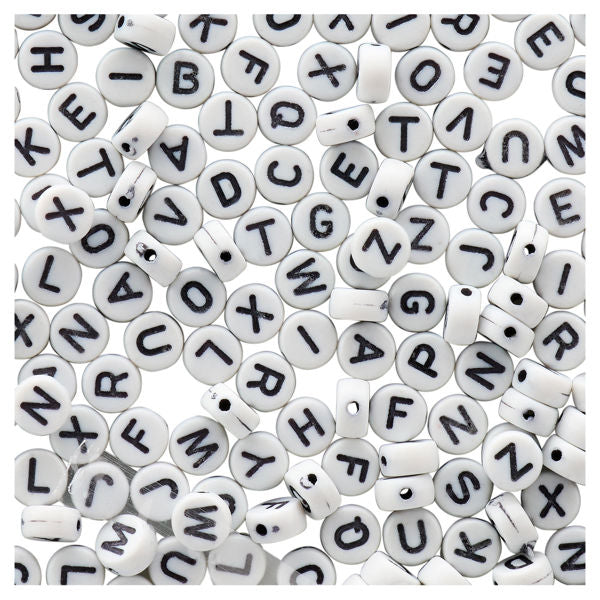 White letter beads with black letters scattered on a white background