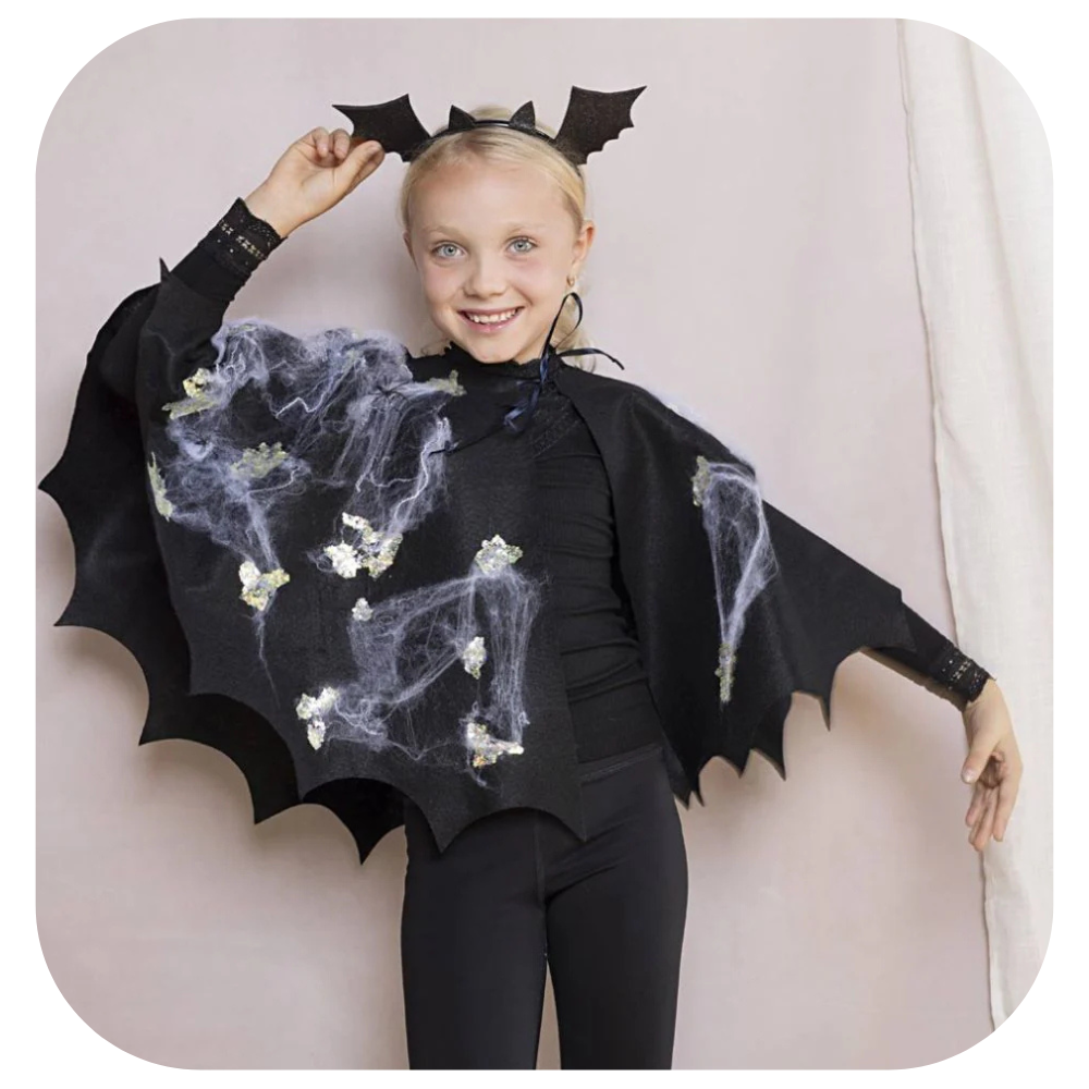A girl wearing a homemade black bat cape with spider webs and bat ears