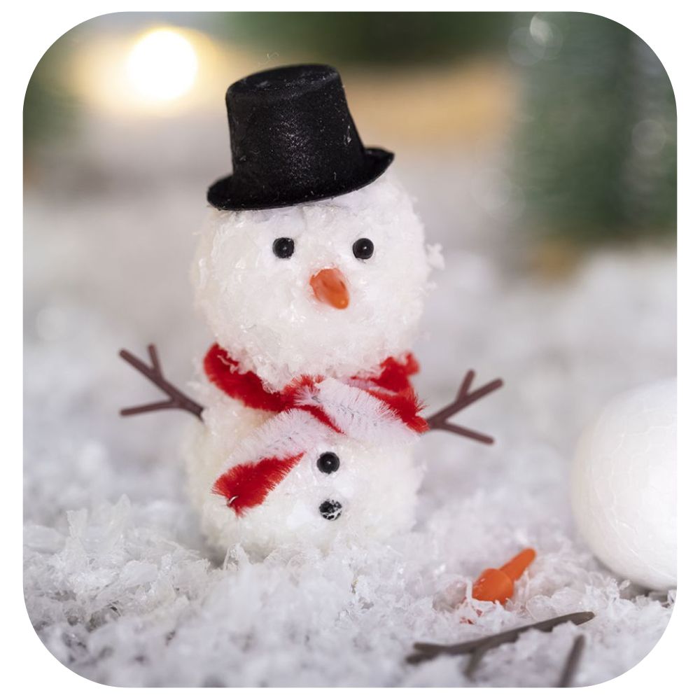 a homemade snowman made from polystyrene balls, artificial snow, glue and other accessories on a floor of snow