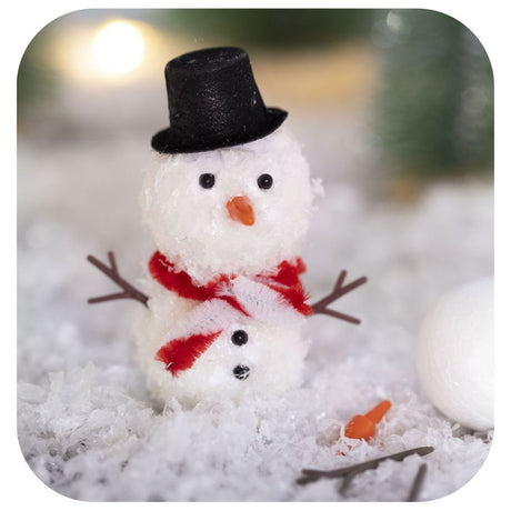 a homemade snowman made from polystyrene balls, artificial snow, glue and other accessories on a floor of snow