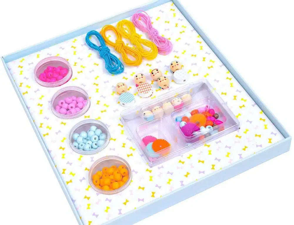 Colorful jewelry-making kit with beads and strings on a white background