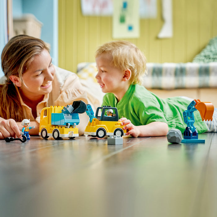 Woman and child playing with toy construction vehicles on a table