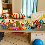 Colorful building blocks on a table in a child's room with toys and furniture around.