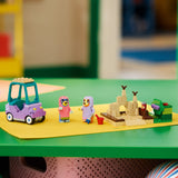 Toy set with a car, people, and a castle on a green surface