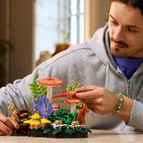 Man playing with a LEGO mushroom and forest set on a table.
