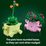 Two toy plant pots with a green succulent and pink flowers on a dark green background.