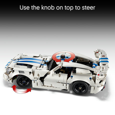 A white and blue building-block toy sports car shown on a gray gradient background with instructional text at the top reading 'Use the knob on top to steer' and red arrow graphics indicating steering.
