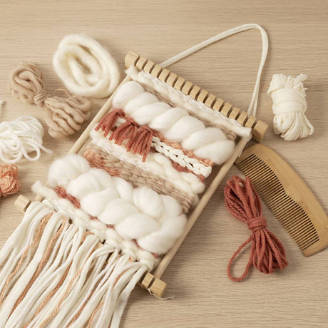 Handmade woven craft with yarn and a comb on a wooden surface