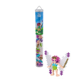 Fairy figure with purple hair and green dress next to a cylindrical tube of building blocks on a white background