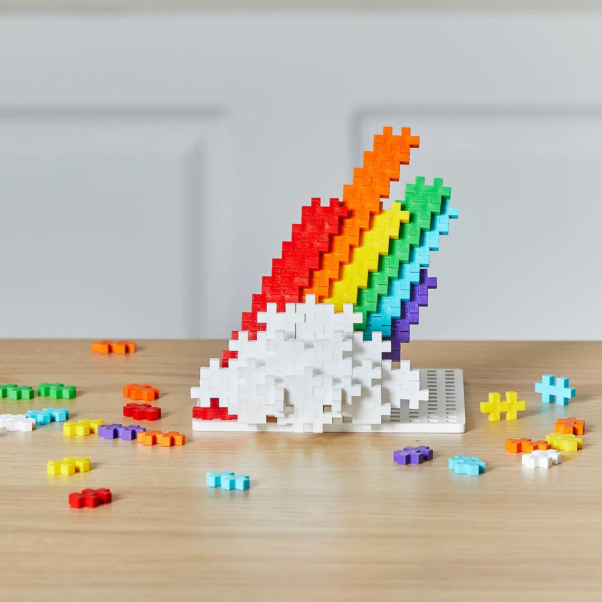 Colorful 3D puzzle of a rainbow-colored character on a wooden surface with scattered pieces.