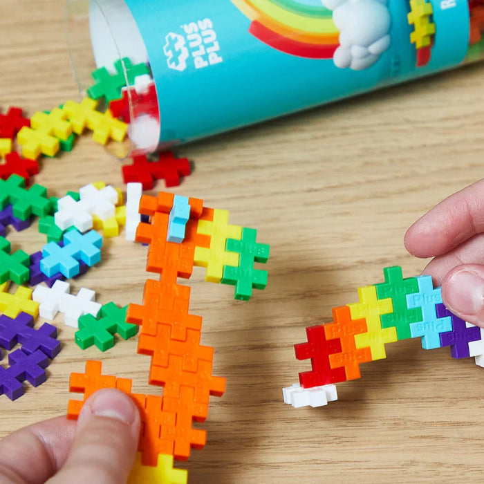 Colorful interlocking toy pieces on a wooden surface with a child's hand interacting with them.