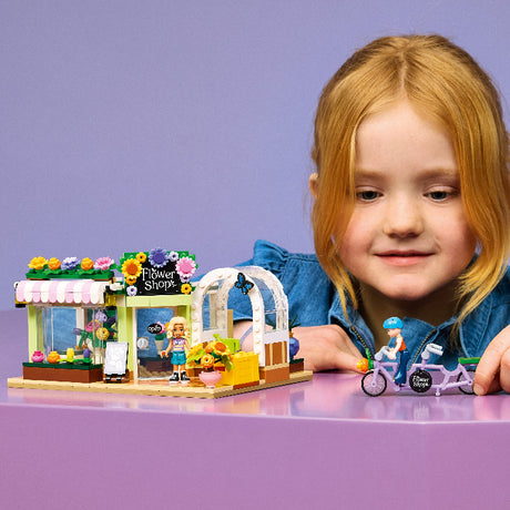 Child with a LEGO Flower Shop set on a purple background