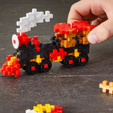 Hand building a pixelated car model with colorful blocks on a dark surface