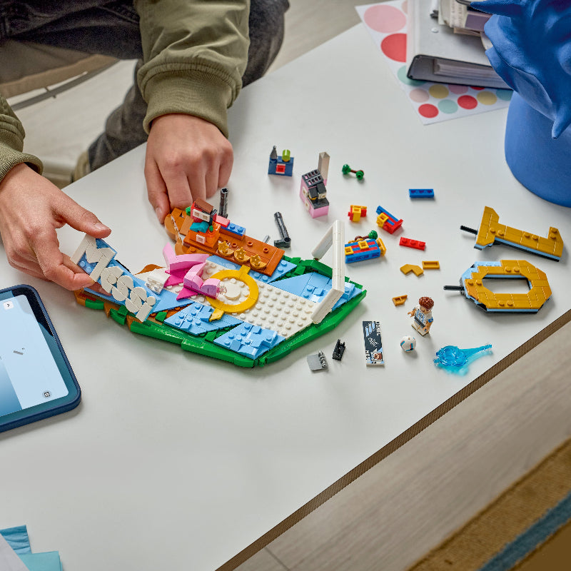 Children playing with LEGO bricks on a table, using a smartphone for reference.