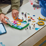 Children playing with LEGO bricks on a table, using a smartphone for reference.