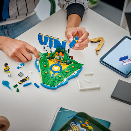 Children playing with a LEGO set on a table, using a tablet for instructions.