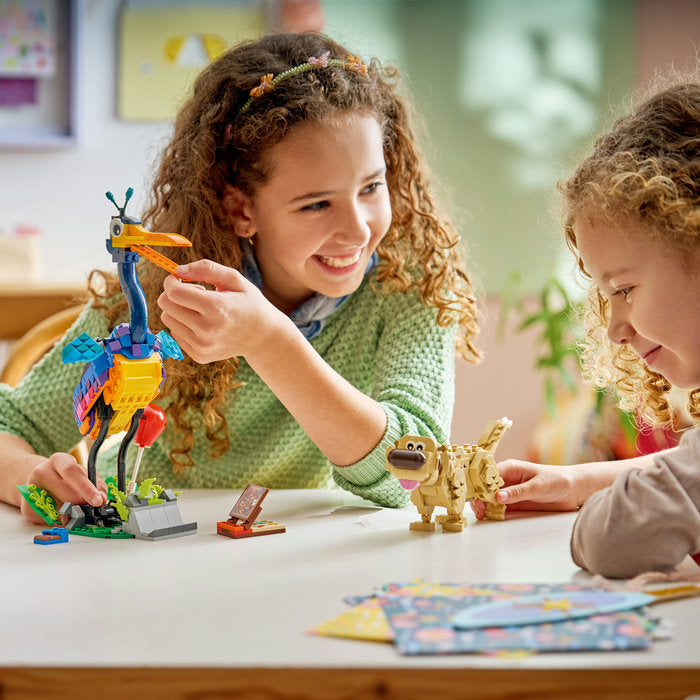 Two children playing with toy figures at a table in a classroom setting.
