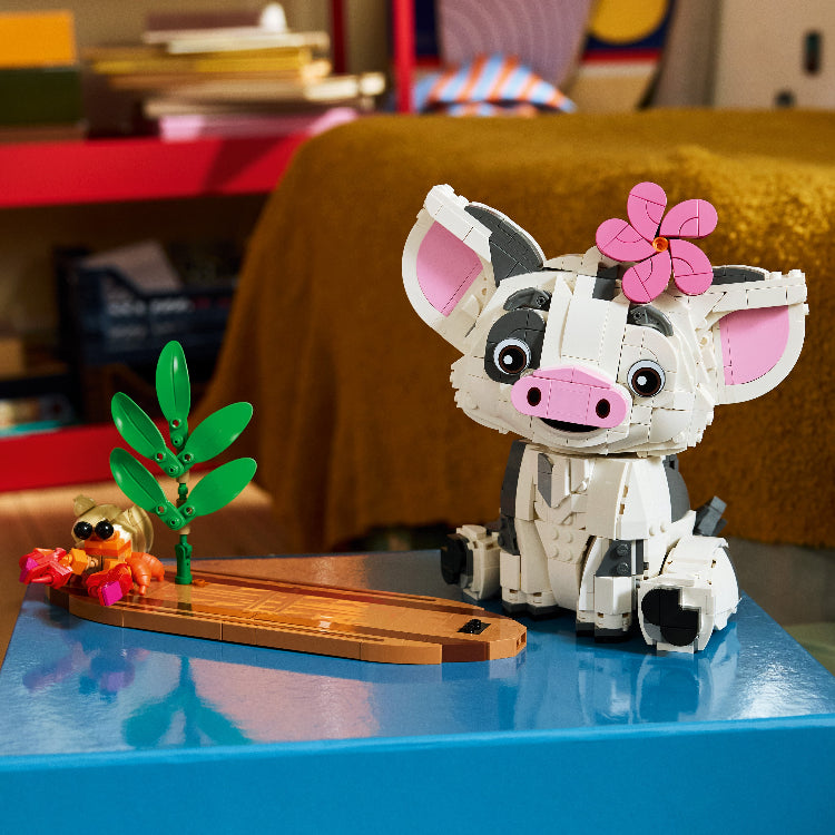 LEGO pig figure with a flower on a blue surface, with a colorful background