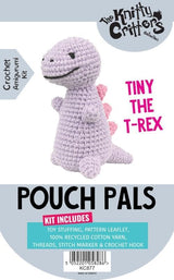 Front cover of a crochet amigurumi kit for making a mini T-rex pouch doll. The cover features a crocheted light purple T-rex with pink spikes, set against a white and gray background with text reading 'Pouch Pals', 'The Knitty Creations Collection', and 'Tiny the T-Rex'.