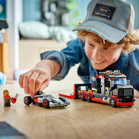 Child playing with a toy truck and car set on a wooden table.