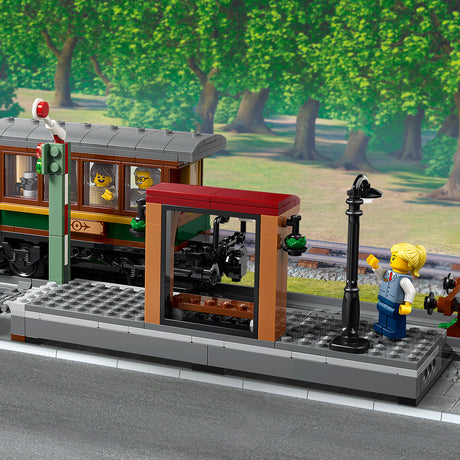 LEGO train set with a station platform and trees in the background