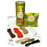 Teeny Crochet kit with its packaging and various yarn skeins, shown on a clean white background. The set includes a green illustrated cardboard tube, a matching book, a bag of white yarn, and several skeins of yarn in brown, orange, beige, white, brown, tan, and black.