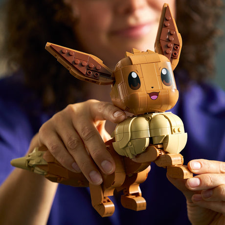 Person holding a detailed toy figure of a creature with large ears and a smiling face.