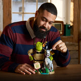 Man holding a Shrek toy set in a cozy indoor setting