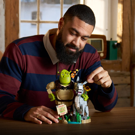 Man holding a Shrek toy set in a cozy indoor setting