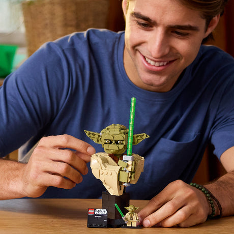 Man playing with a LEGO Yoda figure on a table