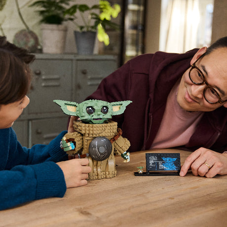 Two people playing with a toy figure of a character from a popular franchise on a wooden table.