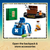 LEGO construction set display showing a blue backpack-style container with a white cross, a green box with studs, a brown chest labeled 'TONY TONY CHOPPER' with a silver syringe, and small accessory bottles and coins on a white background, with text below reading 'Open the backpack & store accessories'.