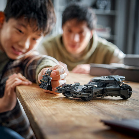 Two children playing with toy vehicles on a wooden table.